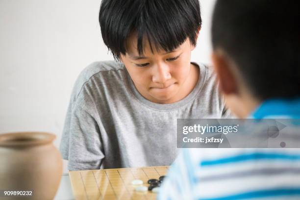 zus en broer spelen van het go spel thuis - board game stockfoto's en -beelden