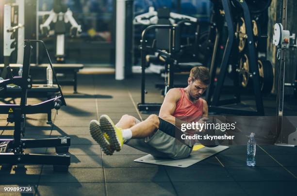 sportlicher mann bemüht sich beim sit-ups mit medizinball in einem fitnessstudio trainieren. - exercise ball stock-fotos und bilder