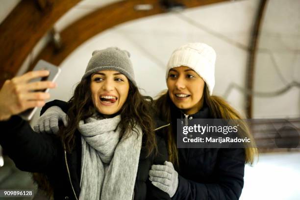 due belle ragazze che indossano caldi vestiti invernali pattinaggio su ghiaccio - capelli ghiaccio foto e immagini stock