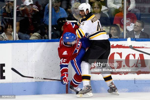 Andy Wozniewski of the Boston Bruins body checks Andre Benoit of the Montreal Canadiens during their NHL Preseason game on September 20, 2009 at the...