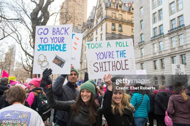 Marchers hold up placards referring to alleged remarks by US President Donald Trump, at the 2018 Women's March in New York City on January 20, 2018.