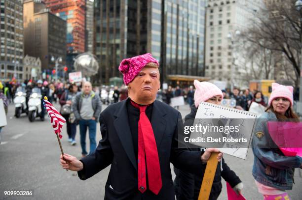 Marcher in a Donald Trump mask holds up a placard protesting the US President, at the 2018 Women's March in New York City on January 20, 2018.