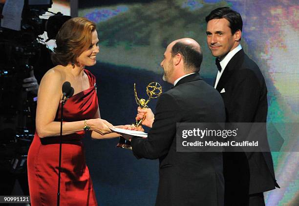 Actress Sigourney Weaver presents an award to writer Matthew Weiner as actor Jon Hamm looks on onstage at the 61st Primetime Emmy Awards held at the...