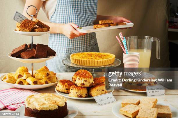 woman displaying goods at a village fair - dessertstandaard stockfoto's en -beelden