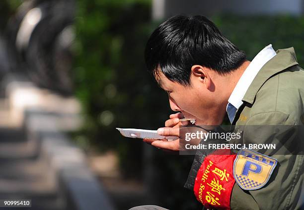 Public security volunteer wearing the ubiquitous red armband eat his lunch in Beijing on September 21, 2009. China approaches the October 1 60th...