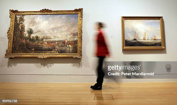 An employee walks past Constable's 'The Opening of Waterloo Bridge 1817 and Turner's 'Helvoetsluys' at the 'Turner and the Masters' exhibition at...