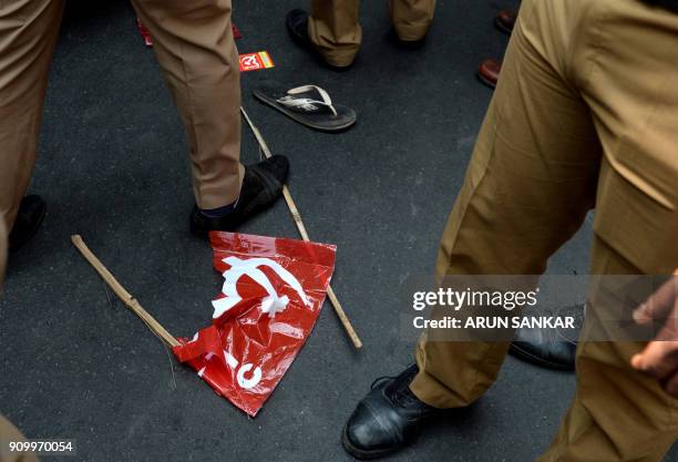 Policemen stand near a damaged communist flag as members of Communist Party of India along with Trade Unions demonstrate during a national wide...