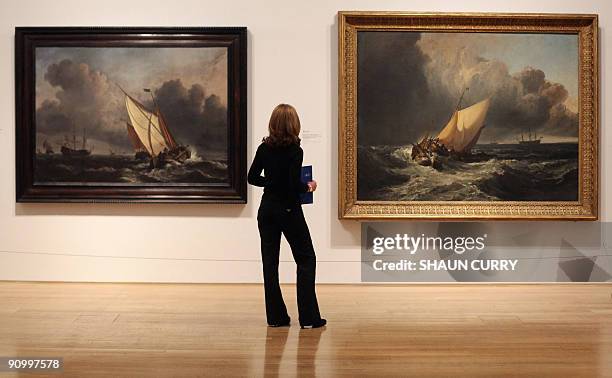 Tate Britain employee looks at paintings by JMW Turner's 'Dutch Boats in a Gale' and William Van de Velde the Younger's 'A Rising Gale' during the...