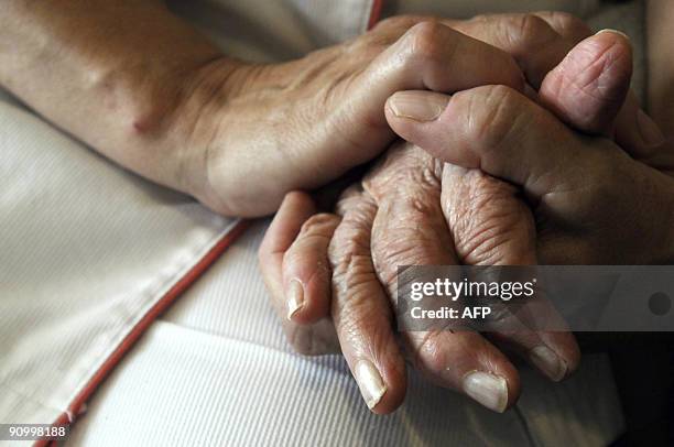 Nurse holds the hands of a person suffering from Alzheimer's disease on September 21, 2009 at Les Fontaines retirement home in Lutterbach , eastern...