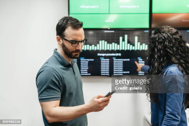 man and woman checking business data in office - digital display sign stock pictures, royalty-free photos & images