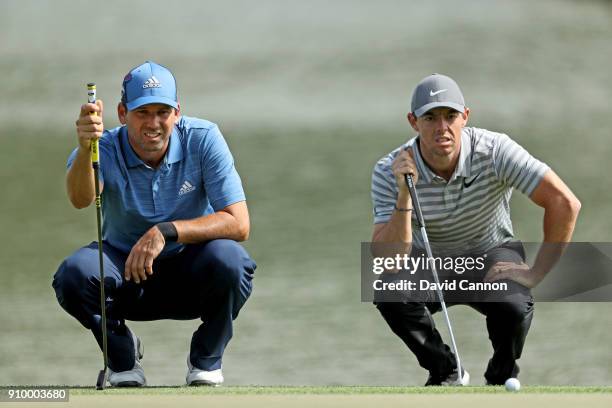 Rory McIlroy of Northern Ireland and Sergio Garcia of Spain line up their putts on the par 4, ninth hole during the first round of the Omega Dubai...