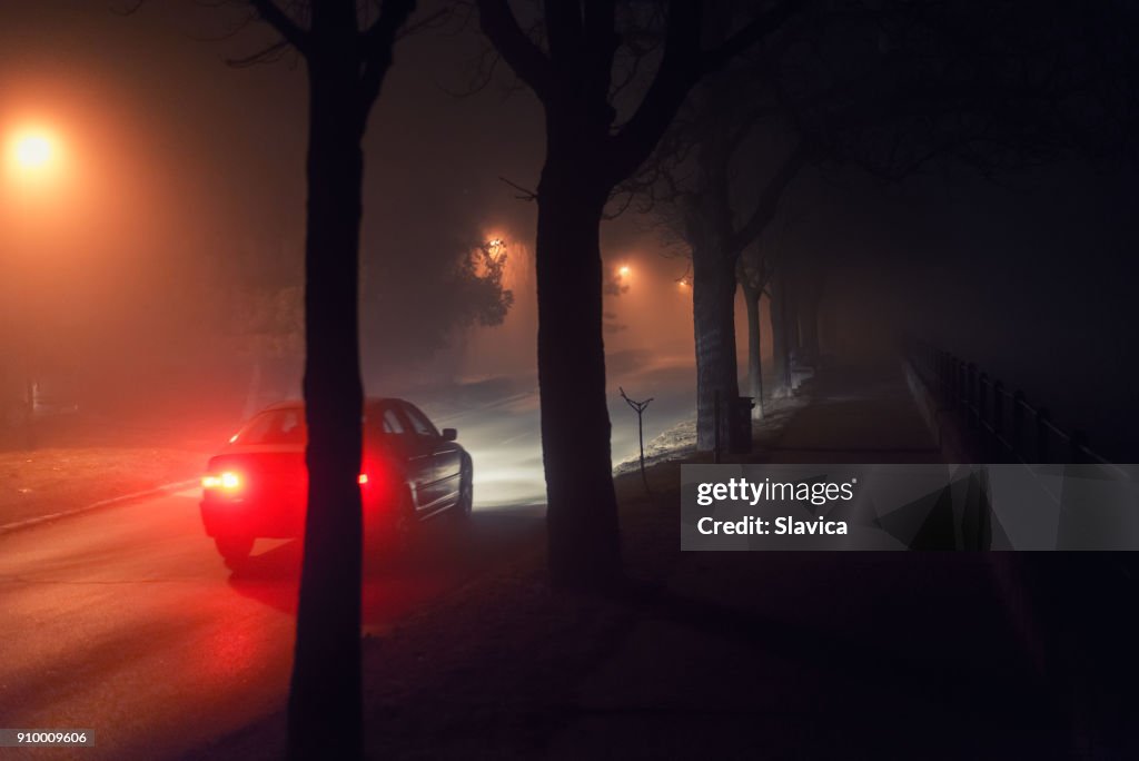 Rijdende auto en loopbrug op mistige nacht