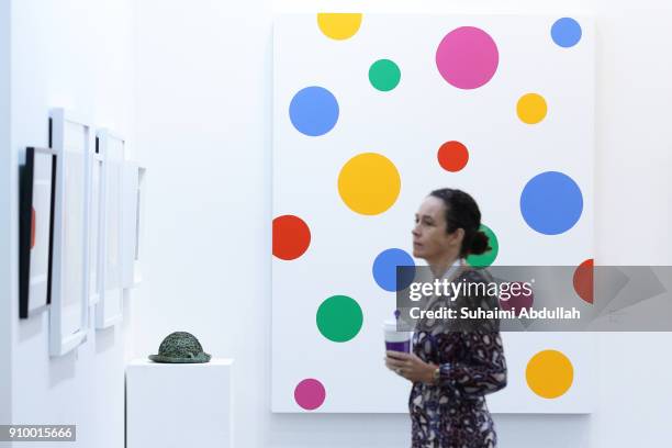Lady stands in front of Japanese artist, Yayoi Kusama acrylic on canvas artwork titled, 'The End of the Universe' at Marina Bay Sands Expo and...