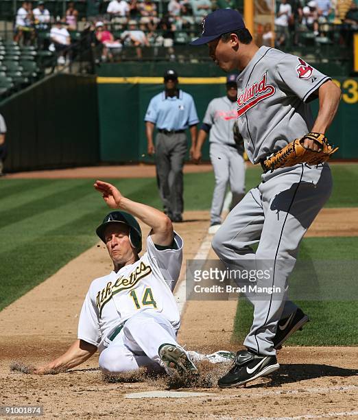 Mark Ellis of the Oakland Athletics slides home safely scoring on a wild pitch as Cleveland Indians pitcher Tomo Ohka waits for the late throw during...
