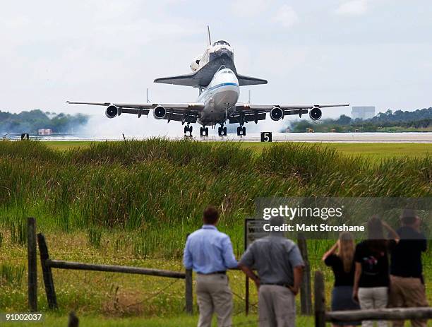 People watch as Space Shuttle Discovery, mounted atop a modified Boeing 747 shuttle carrier, touches down on the shuttle landing facility at NASA's...