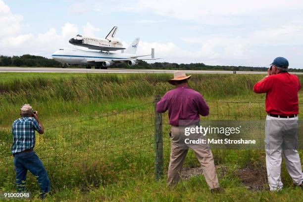 People watch as Space Shuttle Discovery, mounted atop a modified Boeing 747 shuttle carrier, touches down on the shuttle landing facility at NASA's...