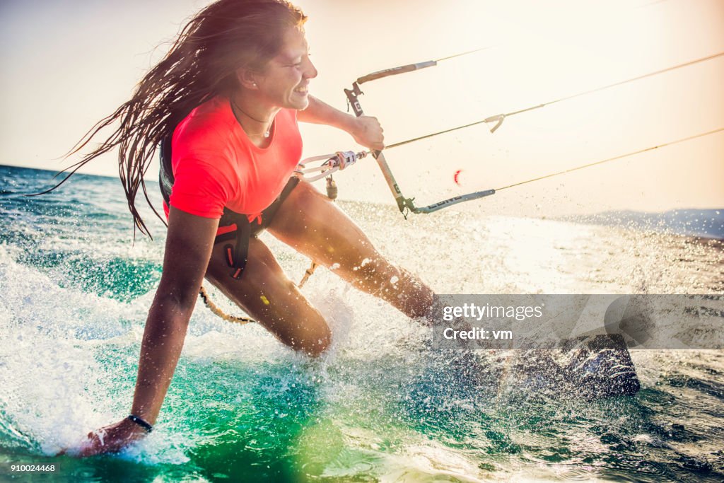 Lächelnde junge weibliche Kiteboarder auf dem Meer