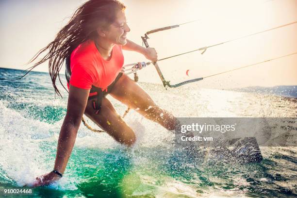 lächelnde junge weibliche kiteboarder auf dem meer - adrenalin stock-fotos und bilder
