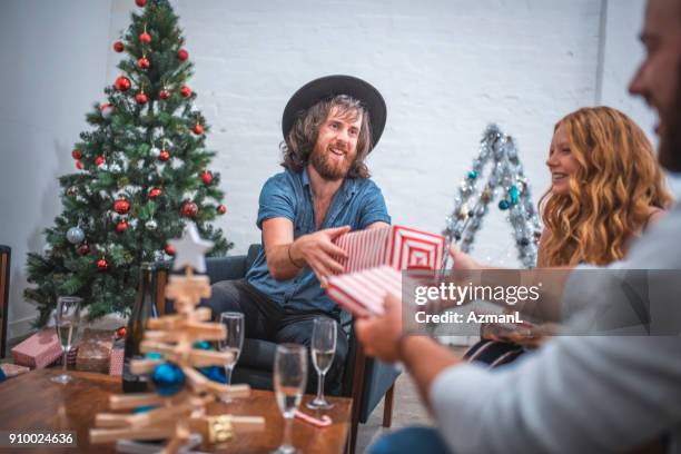 friends exchanging christmas gifts on christmas eve - christmas gift exchange stock pictures, royalty-free photos & images