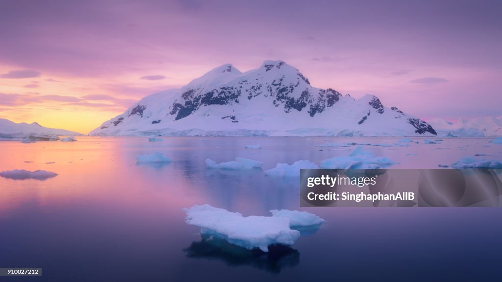 Ice glacier floating in the lagoon with the snowcapped mountain sunset at antarctica