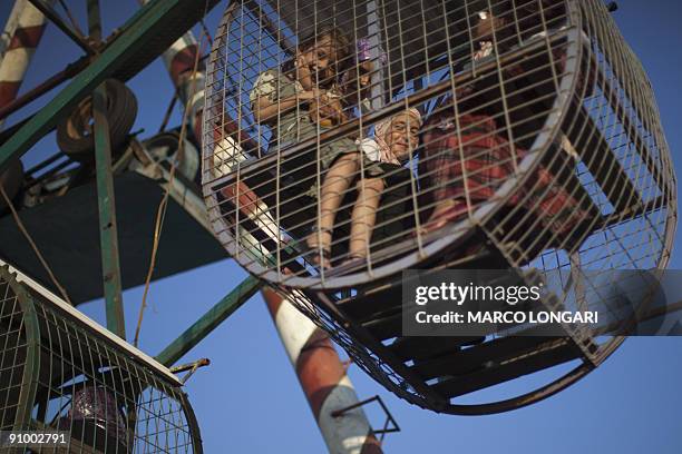 Palestinian children ride a Ferris Wheel at the Al-Bashir amusement park on the outskirts of Gaza City on September 21, 2009 on the second day of Eid...