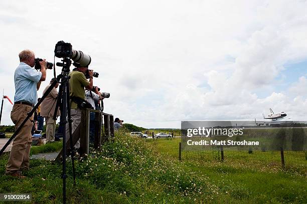 Photographers take pictures as Space Shuttle Discovery, mounted atop a modified Boeing 747 shuttle carrier, lands at the shuttle landing facility at...