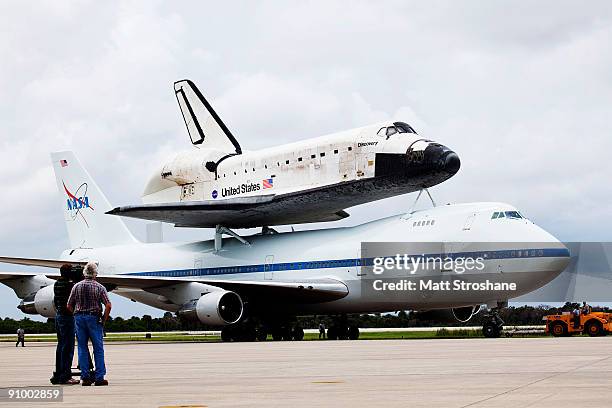 People watch as Space Shuttle Discovery, mounted atop a modified Boeing 747 shuttle carrier, taxis back to the mate-demate area after landing at the...