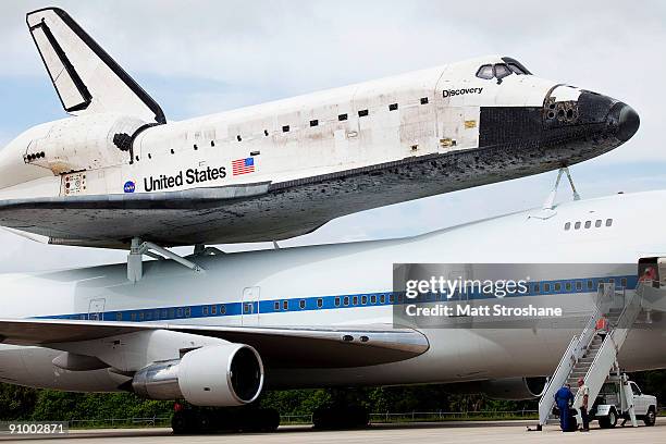 Crew members exit a modified Boeing 747 shuttle carrier with Space Shuttle Discovery mounted atop after landing at the shuttle landing facility at...