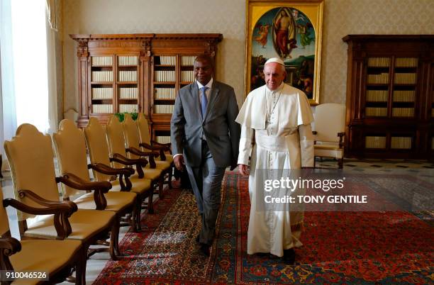 Pope Francis walks along with Central African Republic President Faustin-Archange Touadera during a private audience at the Vatican on January 25,...