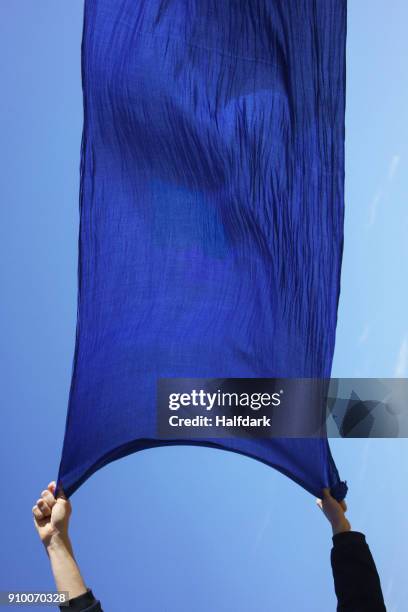 cropped hands of woman holding blue sarong against clear sky - sarong imagens e fotografias de stock