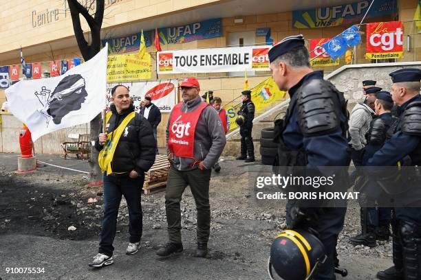 French gendarmes arrive to clear the access to the Baumettes Prison as a participant holds the Corsican flag during a demonstration of prison...