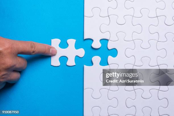 hand holding piece of white puzzle on blue background. business and team work concept. - consensus 2018 foto e immagini stock