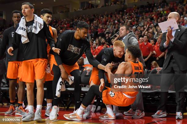 Jeffrey Carroll of the Oklahoma State Cowboys is helped up by teammates after making a three point basket during the game against the Texas Tech Red...