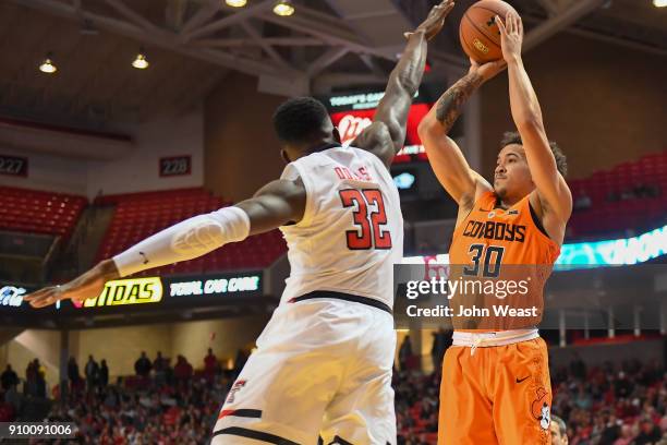 Jeffrey Carroll of the Oklahoma State Cowboys shoots the ball over Norense Odiase of the Texas Tech Red Raiders during the game on January 23, 2018...