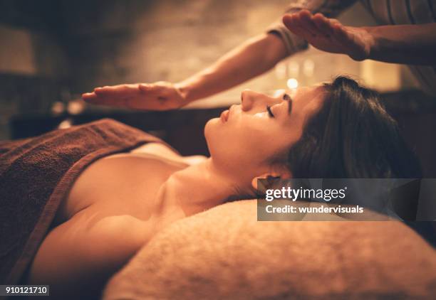 mujer joven relajante masaje corporal y facial en spa - spa treatment fotografías e imágenes de stock