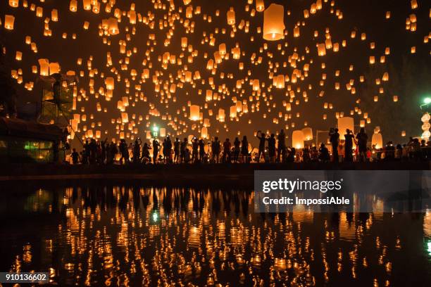 thousands of lanterns in the sky with the reflection on the water with people watching.yeepeng festival, chiangmai, thailand - feriado evento fotografías e imágenes de stock