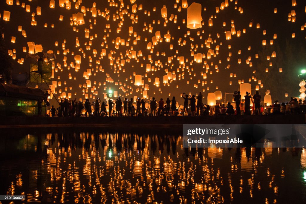 Thousands of Lanterns in the sky with the reflection on the water with people watching.Yeepeng festival, Chiangmai, Thailand