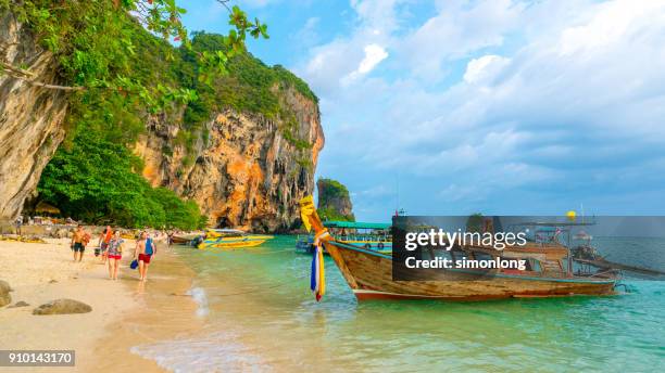 tourists are walking barefoot by the railay beach - praia de railay - fotografias e filmes do acervo