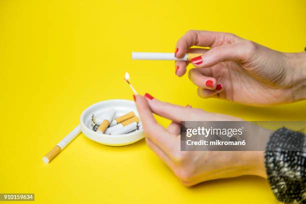 woman lighting a cigarette - zigarettenfilter stock-fotos und bilder