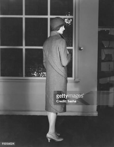 Young woman modelling a three-quarter length coat with spiral trim and a cloche hat, March 1929.