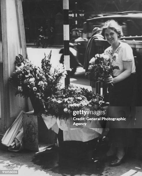 Woman selling roses from her roadside stall, circa 1935.