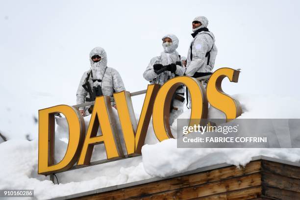 Armed security personnel stand guard on the rooftop of a hotel, next to letters reading "Davos" surrounded by snow, near the Congress Centre on...