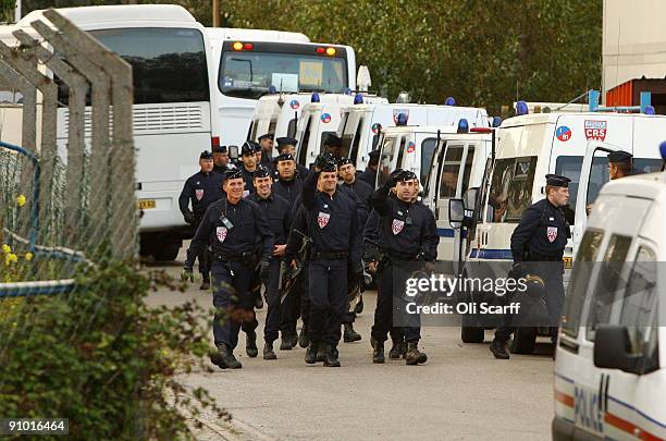 French police officers smile as they return to their vehicles having cleared the makeshift migrant camp known as 'The Jungle' adjacent to a ferry...