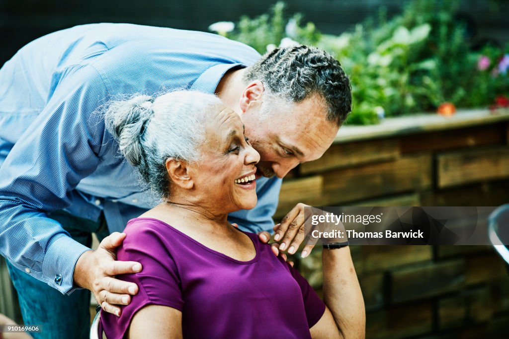 Man hugging and kissing aunt before outdoor dinner party