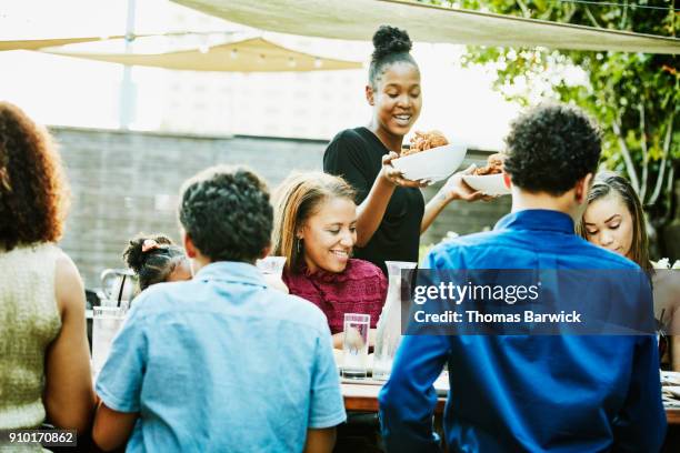 smiling server bringing food to table during outdoor family celebration dinner - texas bowl 個照片及圖片檔