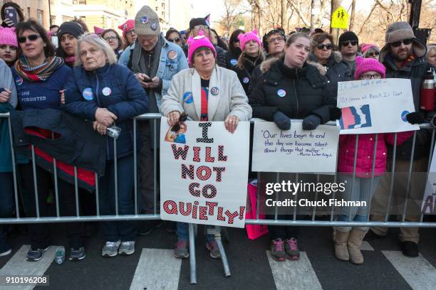 View of unidentified demonstrators, many with signs, as they lean against a barricade on Central Park West prior to the start of the Women's March on...