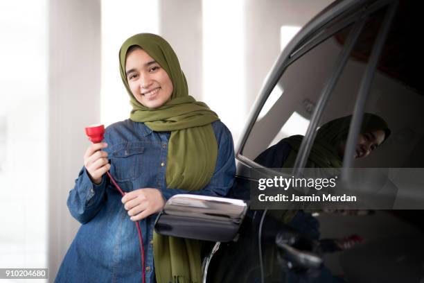 girl with scarf charging new technology electric car - one teenage girl only stockfoto's en -beelden