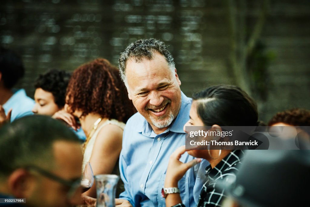 Laughing uncle in discussion with niece during outdoor family dinner party