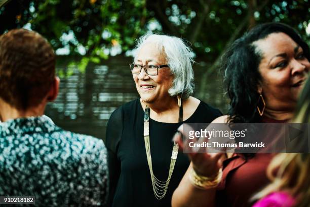 smiling senior woman hanging out with family and friends during outdoor dinner party - 50 60 jahre brille stock-fotos und bilder