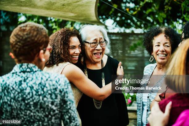 mature daughter embracing senior mother after outdoor family dinner party - seniors and group and diverse foto e immagini stock